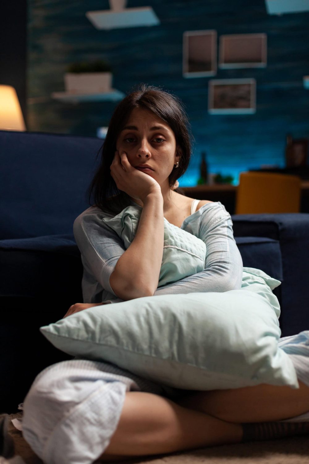 Portrait of sad person with depression problems in living room, sitting on floor and having suicidal thoughts. Depressed anxious woman in pain having mental health difficulties.